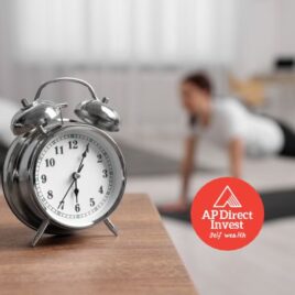 Live longer, live richer! - A vintage alarm clock with a fitness setting in the background, emphasizing financial advice on time-sensitive investments
