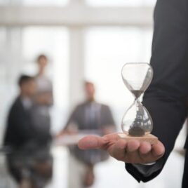 Businessman holding an hour glass, signifies the importance of being on time Businessman holding an hour glass, signifies the importance of being on time