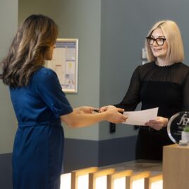 Receptionist handing financial documents to a client – financial advice and personalised client services Receptionist handing financial documents to a client – financial advice and personalised client services